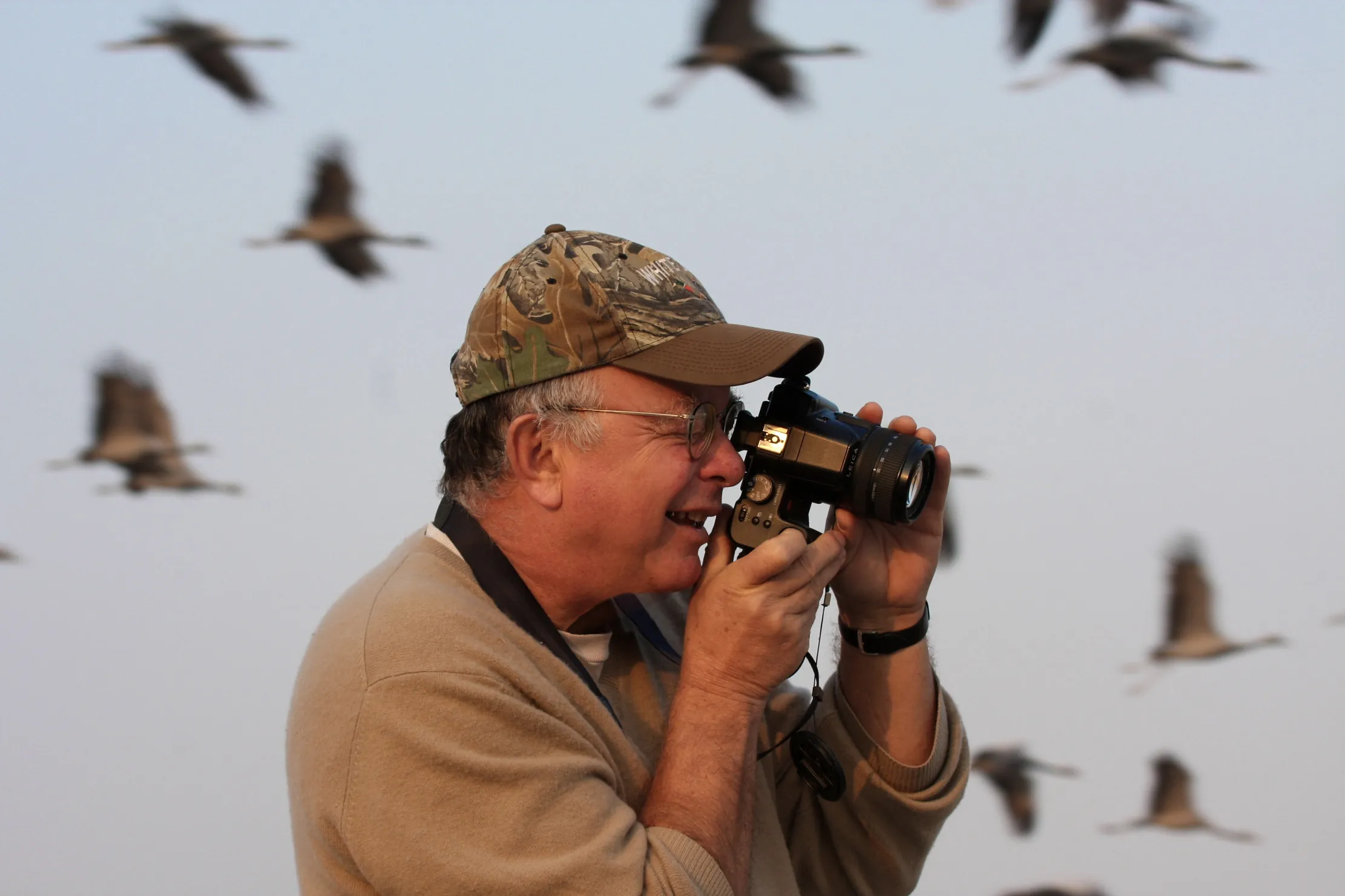 George Archibald taking photos with cranes flying in background