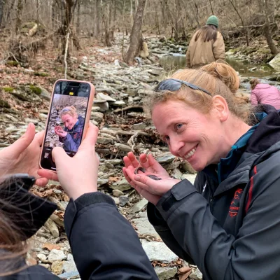 woman taking photo with streamside salamander