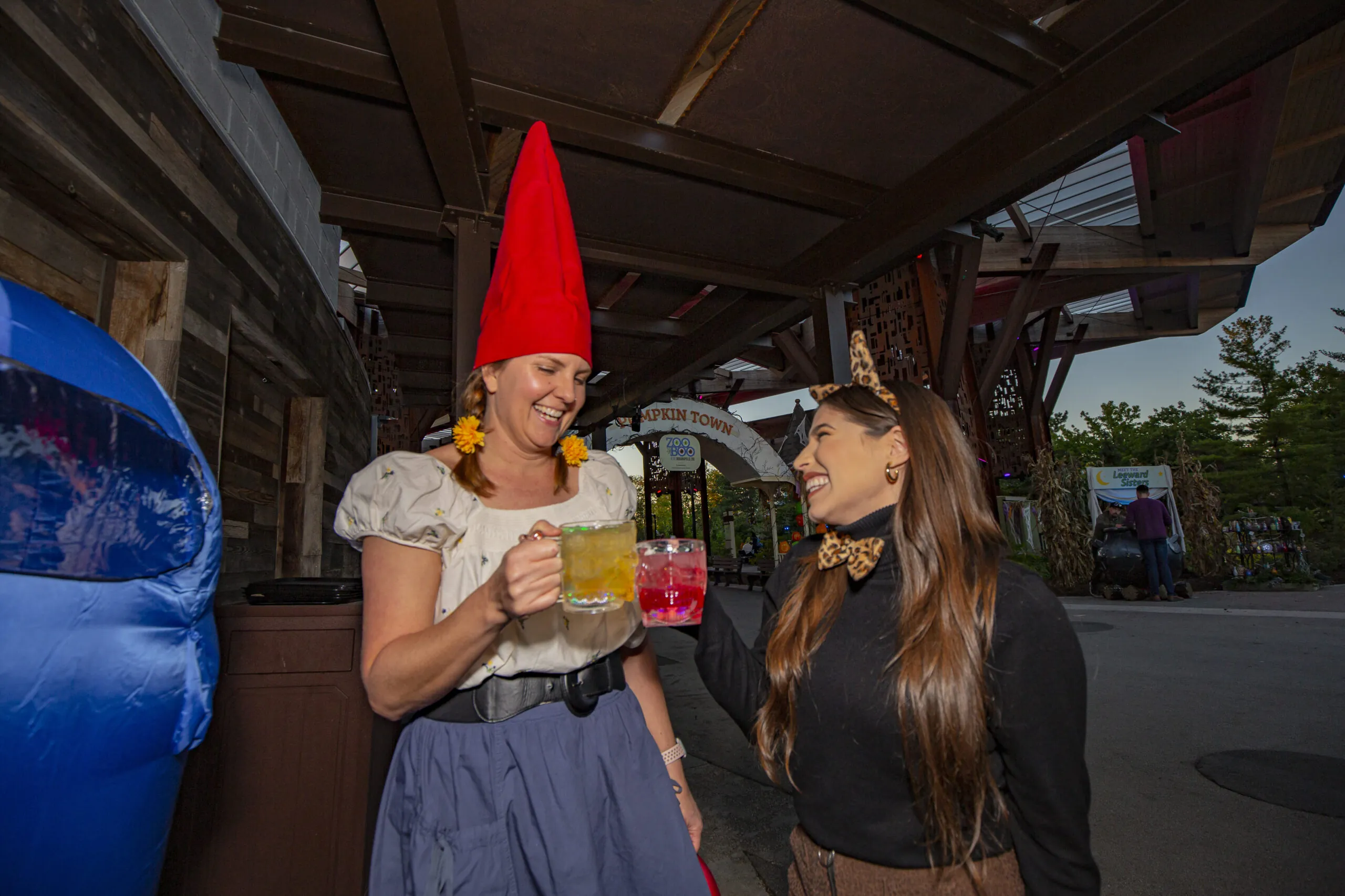 two women clinking adult beverages in costume