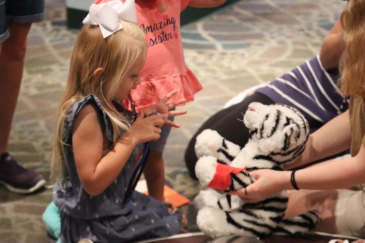 child checking stuffed tiger with stethoscope