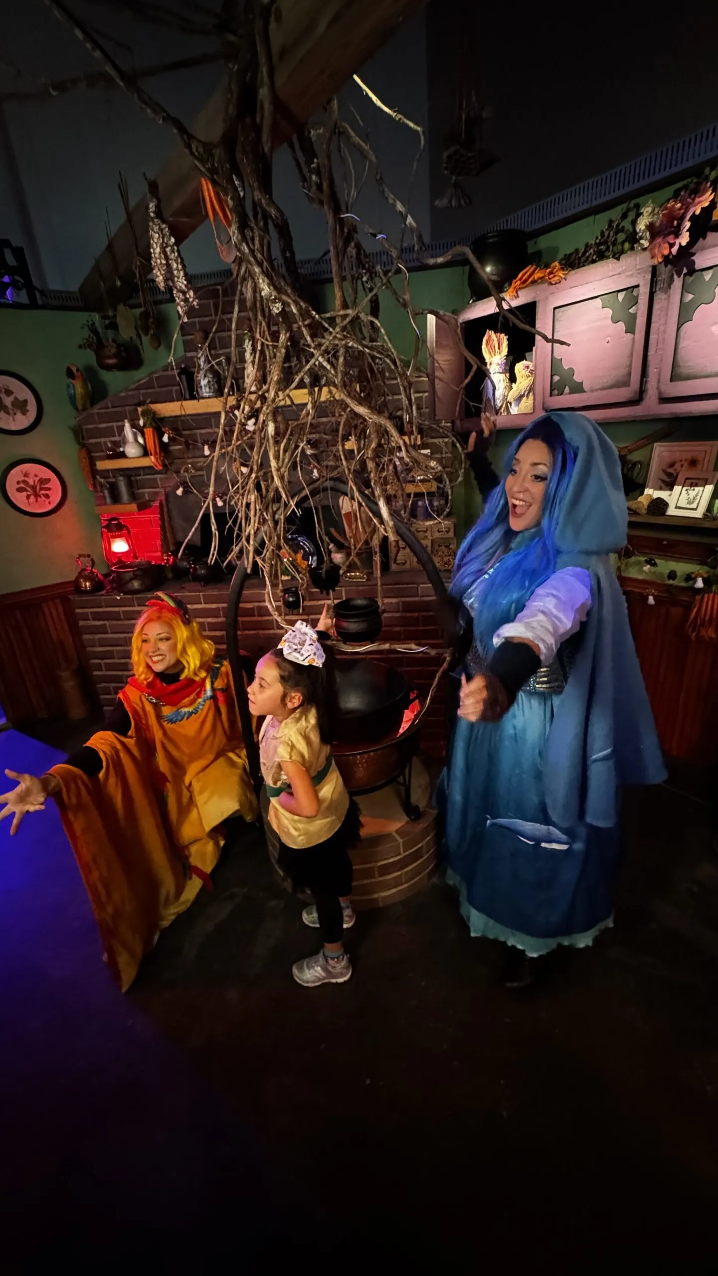 Leeward Sisters standing by their cauldron with little girl in halloween costume