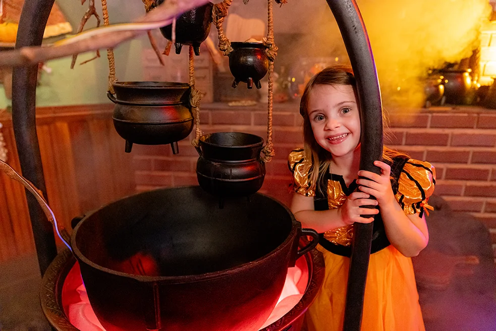 little girl standing next to cauldron