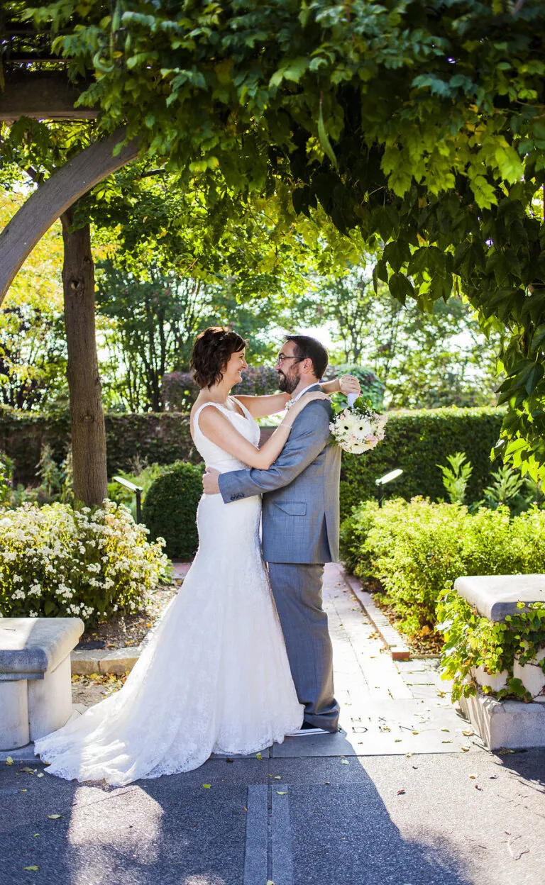 wedding couple under trellis with flowers
