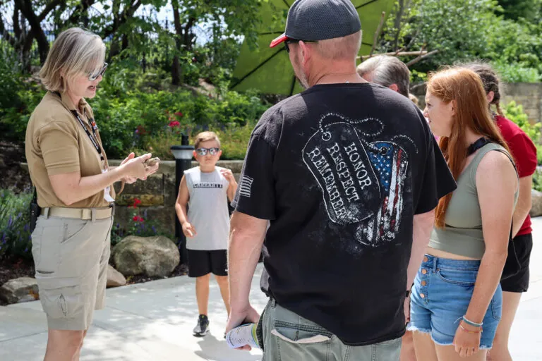 adult volunteer holding lizard with guests